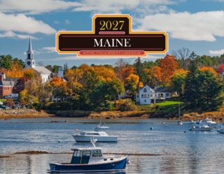 Boats on a calm harbor with autumn trees and a town in the background; a large decorative Maine calendar banner sits across the center.